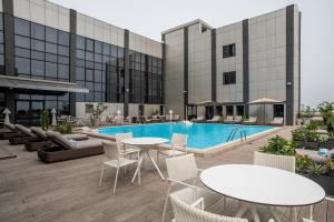 an outdoor patio with tables and chairs and a pool at Krystal Palace Douala in Douala