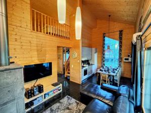 ein Wohnzimmer mit einem Ledersofa und einem TV in der Unterkunft Himos Virpi 8 hlö mökki porealtaalla, ei lisäkuluja! in Jämsä