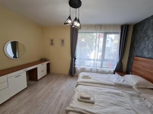 a bedroom with two beds and a mirror and a window at Apartments Ilarion in City Center in Varna City