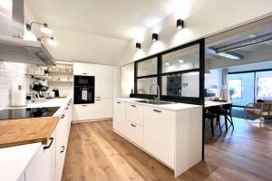 a large kitchen with white cabinets and a dining room at Hauzify I Apartaments Sant Pau in San Pol de Mar