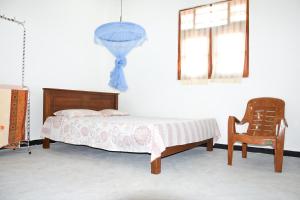 1 dormitorio con 1 cama y 1 silla en Tharaka Homestay, en Weligama