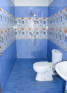 a blue bathroom with a toilet and a sink at Tharaka Homestay in Weligama