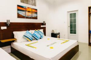 a bedroom with a bed with white sheets and blue pillows at Sunset Beach View in Dhangethi