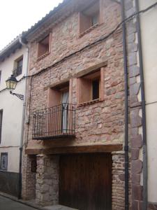 un antiguo edificio de ladrillo con puerta y balcón en El Rincón de Bezas, en Bezas