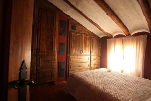 a bedroom with a bed and wooden cabinets and a window at El Rincón de Bezas in Bezas