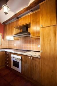 a kitchen with wooden cabinets and a stove top oven at El Rincón de Bezas in Bezas