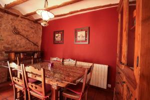 une salle à manger avec une table en bois et des murs rouges dans l'établissement El Rincón de Bezas, à Bezas