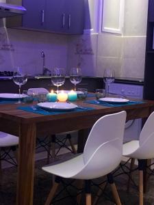 a wooden table with white chairs and wine glasses at 2 bedrooms appartement at Flic en Flac 100 m away from the beach with shared pool furnished terrace and wifi in Flic-en-Flac