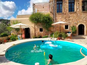 two people swimming in a pool in a yard at Monastiriako in Giannoudi