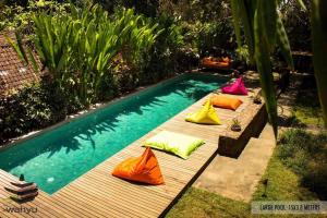 a row of colorful pillows sitting next to a swimming pool at Wahyu Private Peaceful Two Br Rustic Villa W Pool in Seminyak