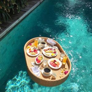 a table with food and drinks in a swimming pool at Wahyu Private Peaceful Two Br Rustic Villa W Pool in Seminyak