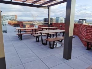 a patio with wooden tables and benches on a roof at Brand New Luxe SOL Canberra CBD One bedroom Apartment in Canberra