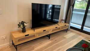 a large flat screen tv sitting on a wooden entertainment center at Brand New Luxe SOL Canberra CBD One bedroom Apartment in Canberra