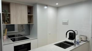 a white kitchen with a sink and a counter at Brand New Luxe SOL Canberra CBD One bedroom Apartment in Canberra