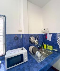um balcão de cozinha com um micro-ondas e um lavatório em Karon House 15C em Praia de Karon