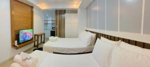 a hotel room with two beds and a flat screen tv at Cozy Unit at the heart of Balanga City in Balanga