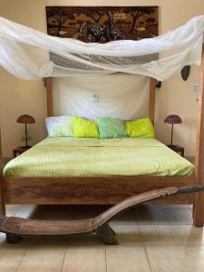 a bedroom with a canopy bed with yellow and green pillows at Villa Rose in Bobo-Dioulasso