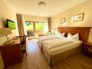 a hotel room with a bed and a desk and a window at Hotel Bärenstüberl in Schönau am Königssee