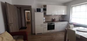 a kitchen with white cabinets and a door leading to a room at Silvia Hüls in Kröv