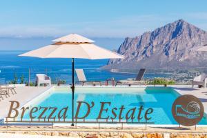 a swimming pool with an umbrella and the ocean at Brezza D'Estate in Valderice