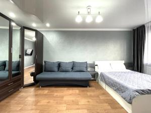 a bedroom with a bed and a couch in it at Квартира целиком в центре 4 спальных места in Petropavlovsk