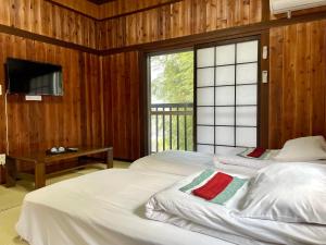 een slaapkamer met 2 bedden, een tv en een raam bij 旅館 竹屋 Takeya in Yufu