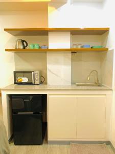a kitchen counter with a microwave and a sink at Cozy Unit at the heart of Balanga City in Balanga