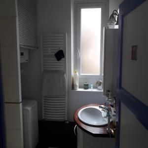 La salle de bains est pourvue d'un lavabo et d'une fenêtre. dans l'établissement Chambre meublée au cœur de ville - chez l'habitant, au Creusot