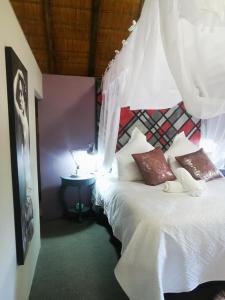um quarto com uma cama branca e uma mesa em The Aces - NUDE - SunEden Family Naturist Resort em Pretoria