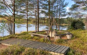 a dock with a swing and a wooden bridge next to a lake at Cozy Home In Ambjrnarp With Kitchen in Ambjörnarp