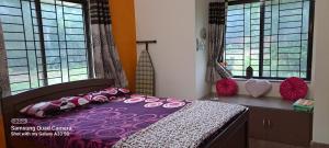 a bedroom with a purple bed and two windows at Shree Homestay in Manipala