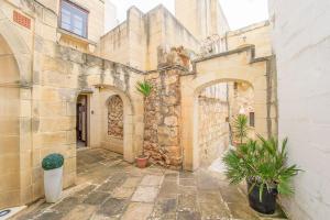 a stone building with plants in a courtyard at Razzett ta' Leli Holiday Home in Xagħra