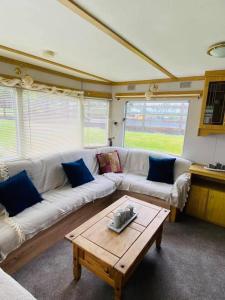 a living room with a white couch and a coffee table at Rowanlea Caravan in Stonehaven