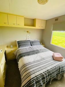 a bedroom with a large bed with a window at Rowanlea Caravan in Stonehaven