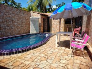 a swimming pool with two chairs and an umbrella at CASA COM PISCINA sensacional in Barreirinhas
