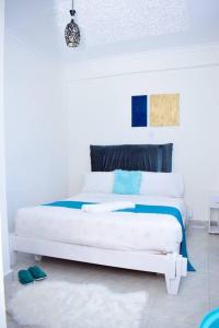 ein weißes Schlafzimmer mit einem weißen Bett mit blauen Akzenten in der Unterkunft Rorot 2 bdrm stay located Annex home away(bright) in Eldoret