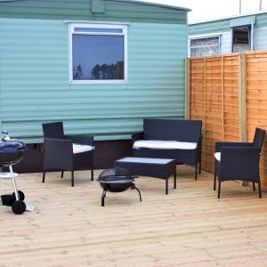 a patio with chairs and a grill and a building at Birchlea Caravan in Stonehaven