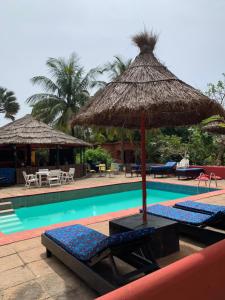 a swimming pool with two lounge chairs and an umbrella at The Gunjur Project Lodge in Gunjur