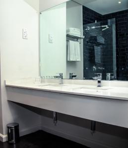 baño con 2 lavabos y espejo grande en The Urban Hotel Lusaka en Lusaka