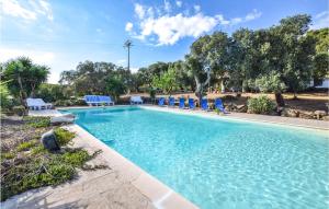 a large swimming pool with blue chairs in a yard at Pet Friendly Home In Sedini With Kitchen in Sedini