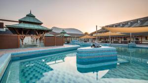 a large swimming pool with a building and a building at Monarchia Cottage Apartman in Mosonmagyaróvár