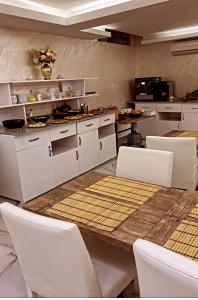 BALPETEK HOTEL في إسطنبول: مطبخ مع طاولة خشبية وكراسي بيضاء