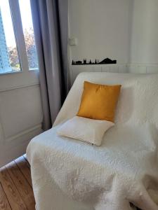 a white bed with a yellow pillow on it at Studio19 in Clermont-Ferrand