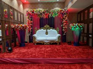 ein Zimmer mit einer weißen Couch und einer Bühne mit Blumen in der Unterkunft THE PRESTIGE HOTEL & CONVENTION in Rourkela