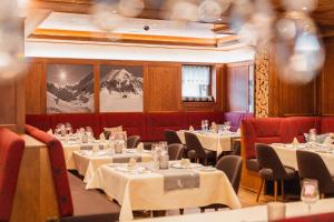 un restaurant avec des tables blanches et des chaises rouges dans l'établissement Hotel Jagdhaus Monzabon, à Lech am Arlberg