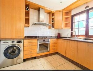 a kitchen with wooden cabinets and a washer and dryer at VILLA ANGELINA in Playa Blanca