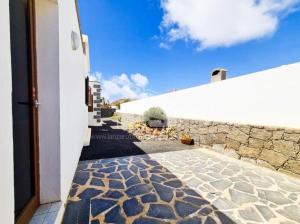 a stone walkway leading to a white building with a wall at VILLA ANGELINA in Playa Blanca