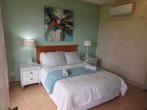 um quarto com uma cama com duas mesas de cabeceira e dois candeeiros em Brookes Hill suites no 18 em Port Elizabeth
