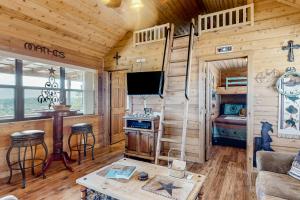 een woonkamer in een blokhut met een fornuis en een tv bij Rock of Ages Cabin at Amazing Grace Canyon in Luckenbach