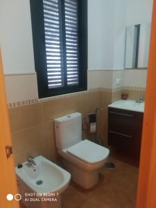 uma casa de banho com um WC, um lavatório e uma janela em Agradable casa rural con chimenea y buenas vistas em Cañaveral de León